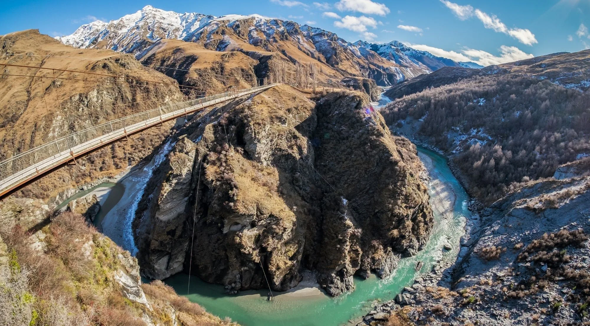 Aerial view of a deep canyon with a road bridge above a wide bend in the river