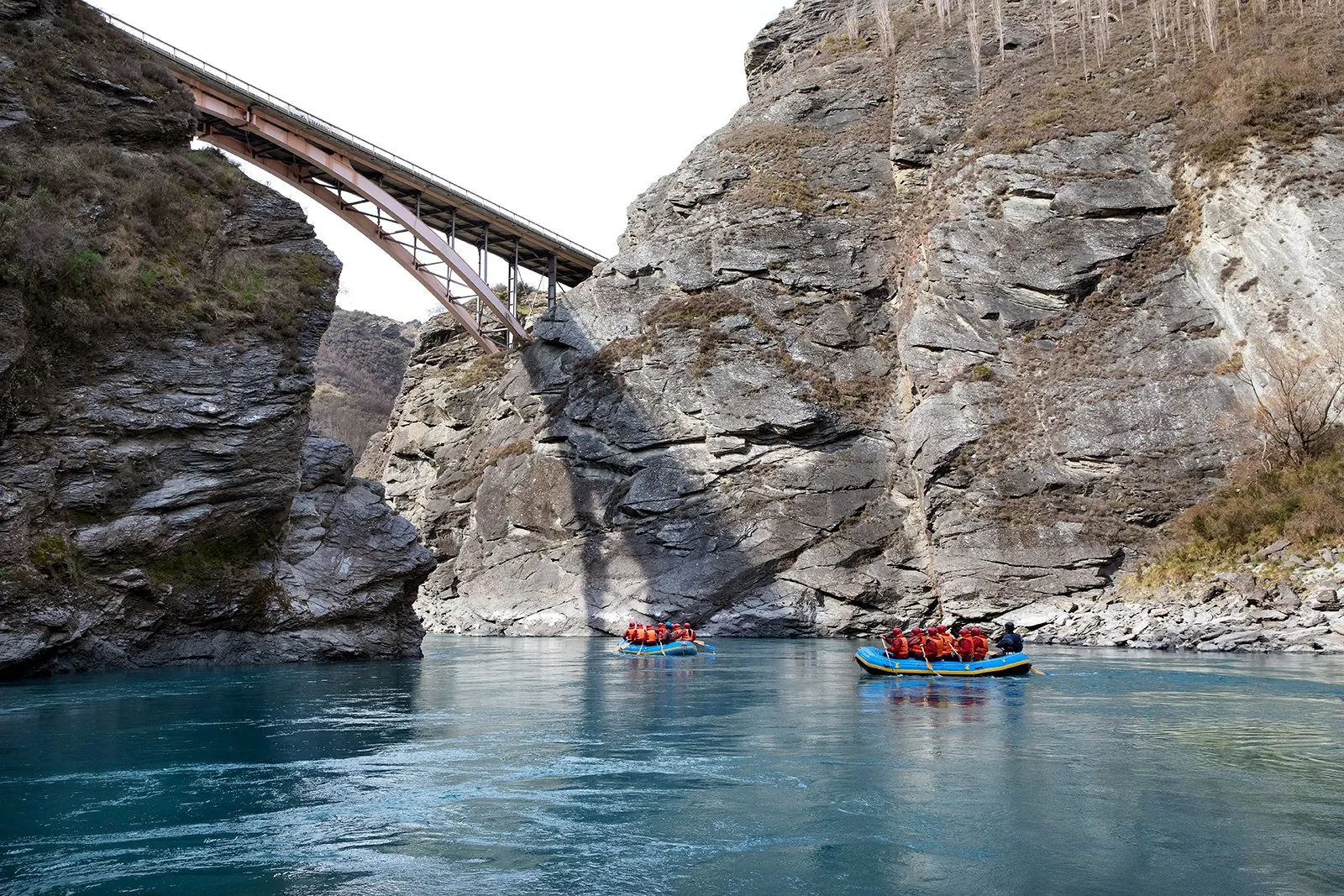 Rafts passing beneath a bridge slung across the canyon